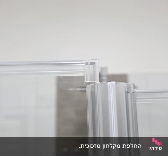 תקריב של גומיות אטימה שקופות מורכבות על דלתות זכוכית במקלחון